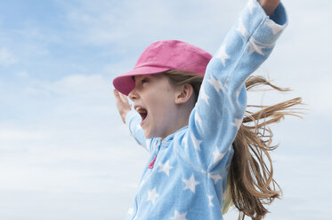 Girl wearing pink cap with arms raised in wind - CUF40378