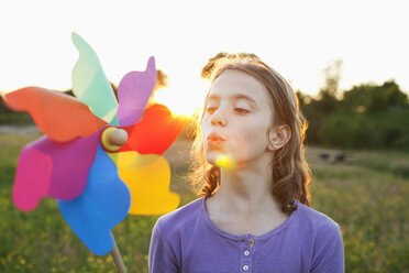 Girl blowing toy windmill - CUF40437