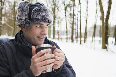 Mature man having hot drink outside in winter - CUF40445