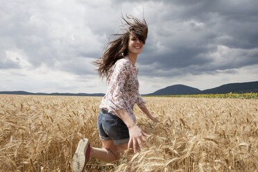 Mittlere erwachsene Frau läuft durch ein Weizenfeld - CUF40516