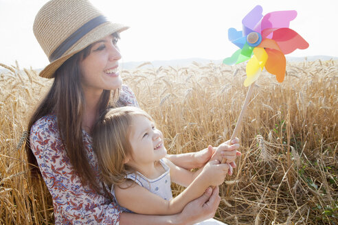 Mother and daughter in wheat field holding windmill - CUF40518