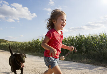 Mädchen und Hund laufen durch ein Feld - CUF40521