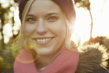 Portrait of young woman in park, wearing knit hat and scarf - CUF40530