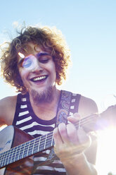Junger Mann spielt Gitarre im Sonnenschein - CUF40543