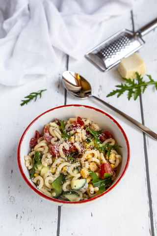 Schüssel Nudelsalat mit Mais, Gurken, Tomaten, Rucola und geriebenem Parmesan, lizenzfreies Stockfoto