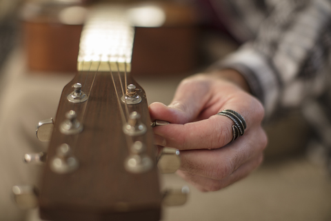 Nahaufnahme einer Männerhand, die eine Gitarre stimmt, lizenzfreies Stockfoto