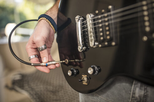 Close-up of man's hand plugging electric guitar - ZEF15828