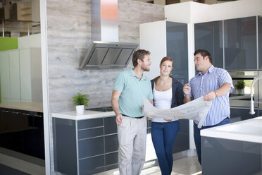 Young couple with salesman in kitchen showroom - CUF40606