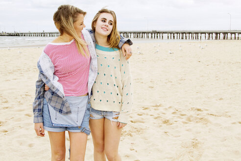 Freundinnen stehen am Strand mit Arm um - CUF40610