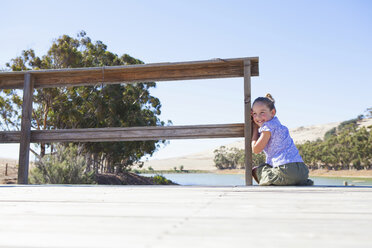 Girl sitting on pier, looking over shoulder - CUF40787