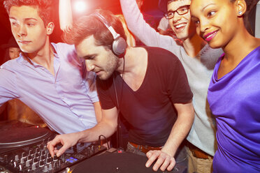 Disc jockey with group of people behind mixing desk - CUF40809