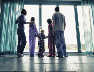 Familie im Pyjama schaut aus dem Fenster - CUF40893