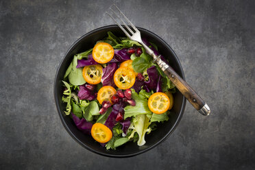 Bowl of mixed green salad with red cabbage, kumquat and pomegranate seeds - LVF07259
