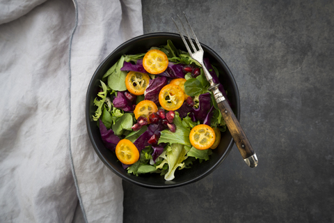 Schüssel mit gemischtem grünem Salat mit Rotkohl, Kumquat und Granatapfelkernen, lizenzfreies Stockfoto