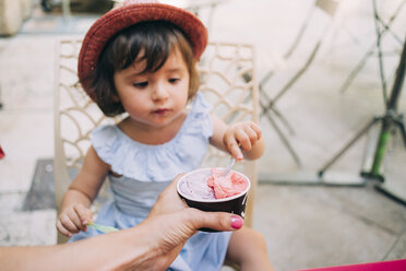Niedliches Kleinkind, das im Arm seiner Mutter ein Eis isst - GEMF02115
