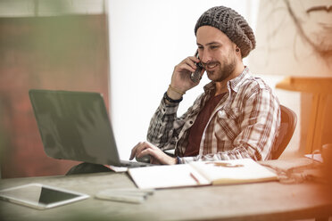 Künstlerin mit Laptop und Mobiltelefon im Atelier - ZEF15864