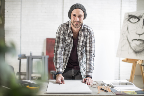 Portrait of confident artist standing at his desk in studio stock photo