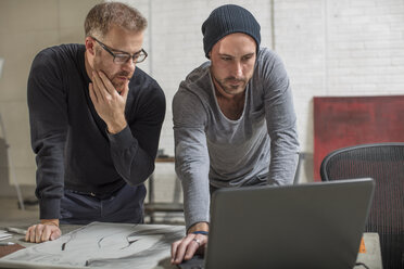 Artist using laptop with man in studio - ZEF15878