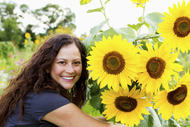 Porträt einer jungen Frau und Sonnenblumen im Kleingarten - CUF41108