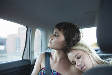 Women in backseat of car, one with head on friend's shoulder - CUF41261