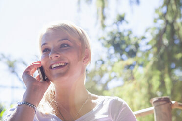 Frau benutzt Mobiltelefon im Garten - CUF41297