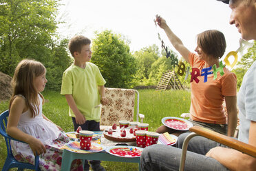 Family with two children celebrating birthday outdoors - CUF41318