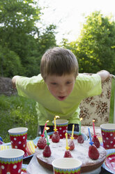 Close up portrait of young boy blowing out birthday candles - CUF41323