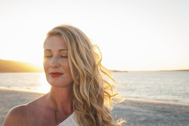 Blonde Frau mit geschlossenen Augen am Strand in der Abenddämmerung, Kapstadt, Südafrika - CUF41325