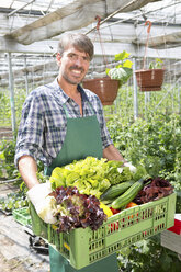 Portrait of organic farmer carrying a tray of fresh produce - CUF41468