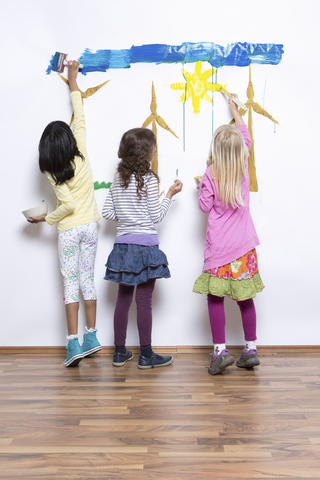 Drei Mädchen malen Windräder an die Wand, lizenzfreies Stockfoto