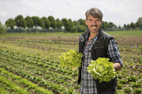 Porträt eines Biobauern mit Salat in der Hand, lizenzfreies Stockfoto