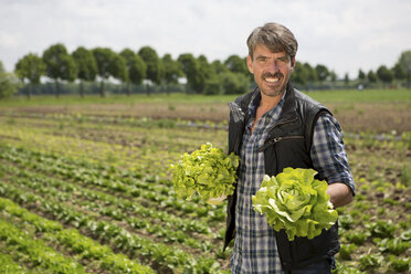 Portrait of organic farmer holding lettuce - CUF41478