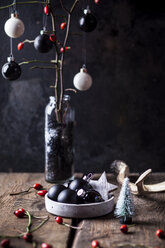 Weihnachtsdekoration mit weißen und schwarzen Kugeln und Zweigen mit Hagebutten in einer Vase - SBDF03625