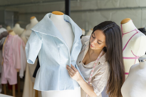 Junge Modedesignerin bei der Anprobe von Kleidern an einem Schneidermodell - AFVF00763