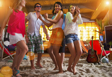 Freunde tanzen auf Sand in einer Strandbar - CUF41510