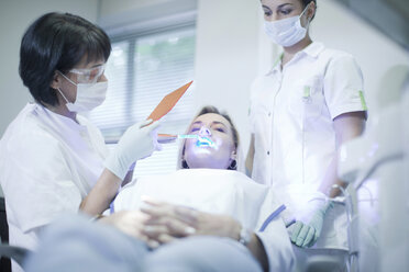 Dentist applying ultraviolet light to patients teeth - CUF41534