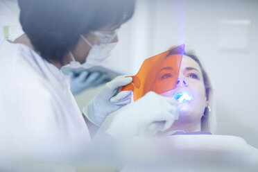 Zahnärztin bei der Anwendung von ultraviolettem Licht an den Zähnen eines Patienten - CUF41535
