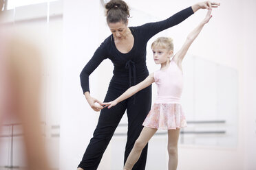 Young ballerina practicing pose with teacher - CUF41575