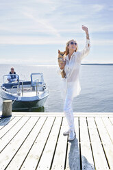 Junge Frau fotografiert sich selbst mit Hund am Pier, Gavle, Schweden - CUF41642