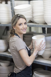 Potter stacking bowls onto shelf at crockery factory - CUF41742