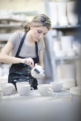 Potter brushing mug at crockery factory - CUF41744