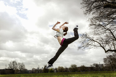 Woman jumping in mid air with bent leg - CUF41824