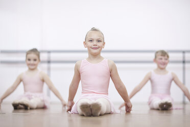 Junge Ballerinas in Pose, während sie auf dem Boden sitzen - CUF41919