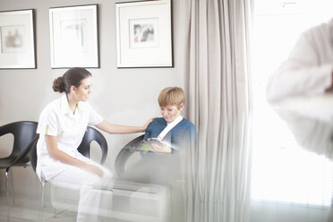 Krankenschwester unterhält sich mit einem jungen Patienten an der Rezeption eines Krankenhauses - CUF41926