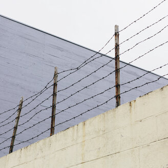 Stacheldrahtzaun an der Spitze einer Mauer in einer Stadt. - MINF00025