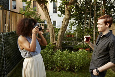 Junge Frau fotografiert Mann im Garten - CUF41936