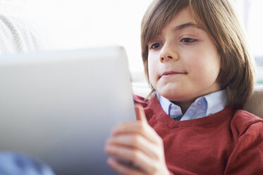 Boy on sofa using digital tablet - CUF41946