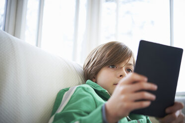 Junge auf Sofa mit digitalem Tablet - CUF41948