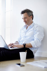 Man sitting on floor sing laptop - CUF41965