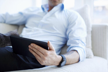 Ausschnitt aus der Mitte eines Mannes, der ein digitales Tablet hält - CUF41974